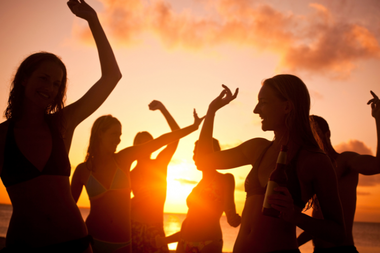 group of friends dancing at sunset